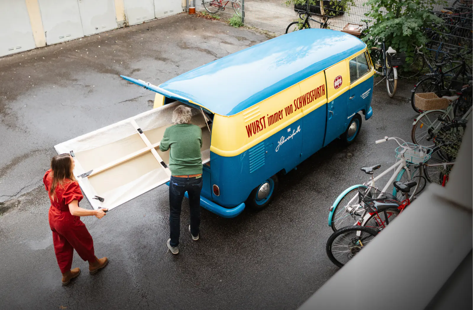 Rebecca Gischel und Karl Schweisfurth verladen ein Gemälde in einen historischen Herrmannsdorfer Lieferwagen